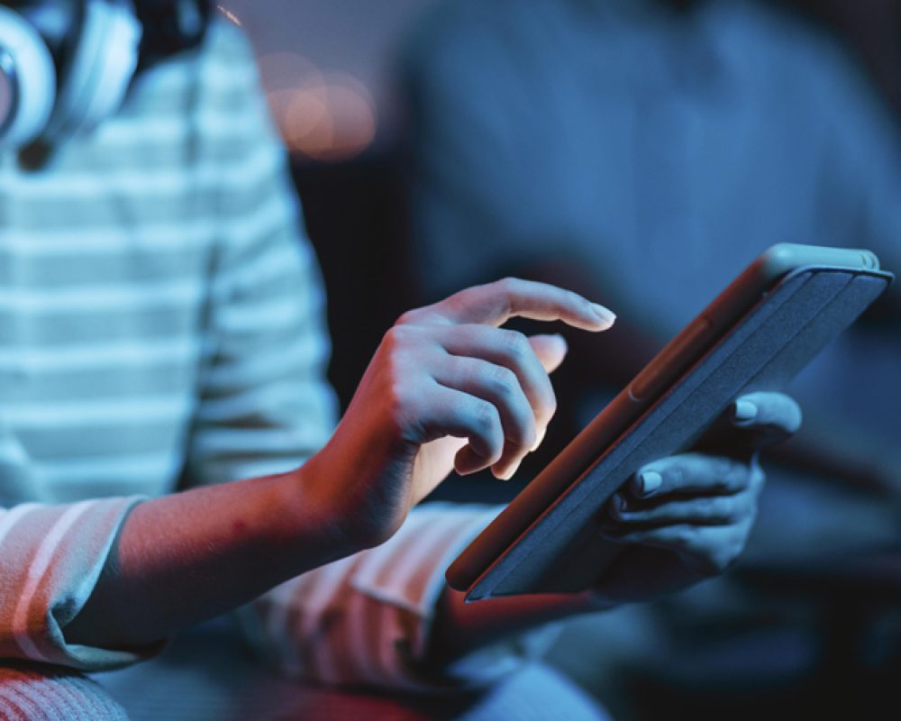 side-view-of-woman-at-home-using-headphones-and-tablet